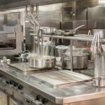 Commercial stainless steel kitchen equipment cooking line featuring heavy-duty griddles, ranges, overhead shelving, and stock pots