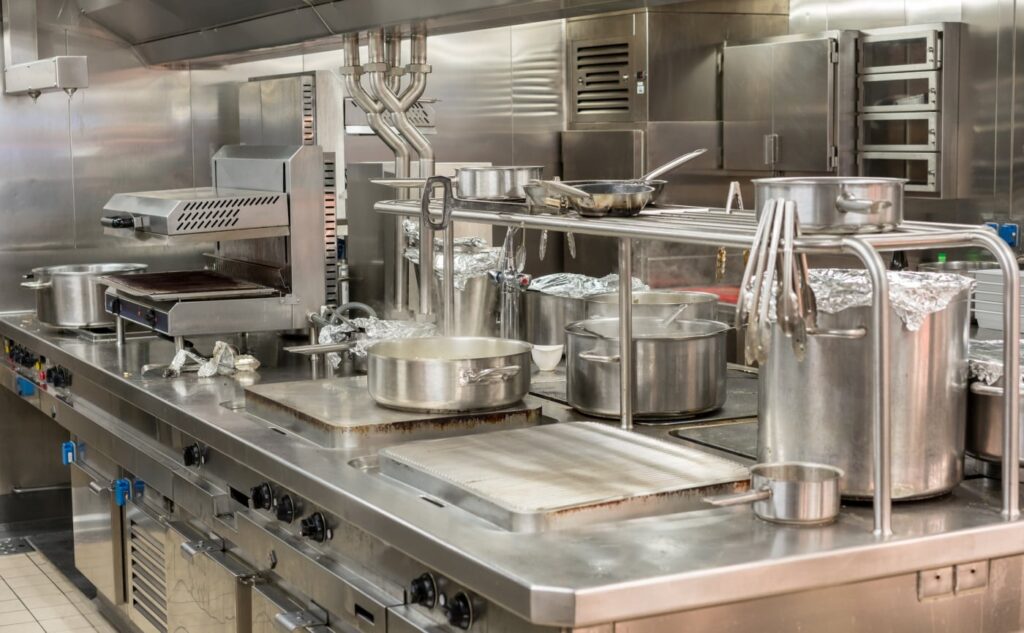 Top commercial kitchen equipment setup featuring heavy-duty stainless steel ranges, griddles, and professional cookware.